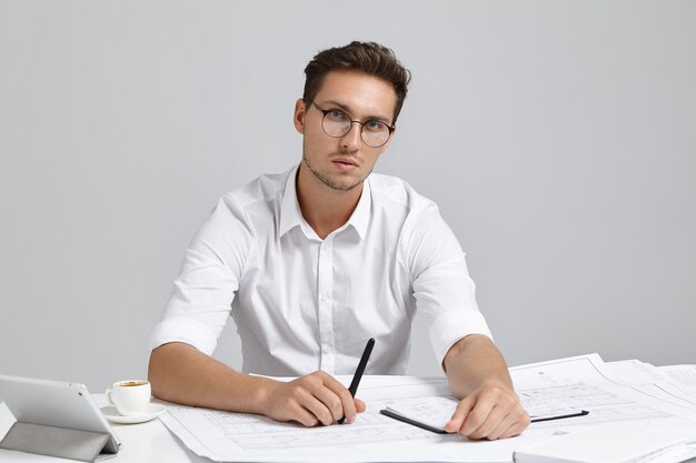 Giovane uomo seduto alla scrivania e fare il lavoro di ufficio