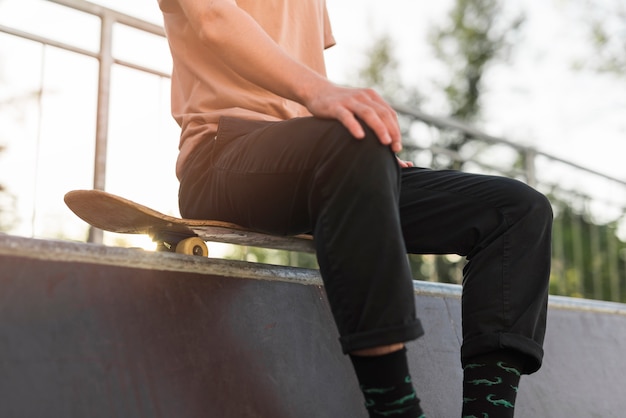 Giovane uomo seduto su uno skateboard