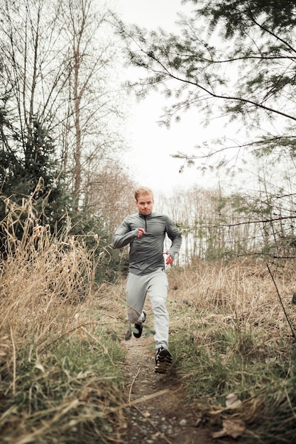 Giovane uomo sportivo che corre nella foresta