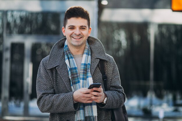 Giovane viaggiatore bello dell'uomo che per mezzo del telefono fuori