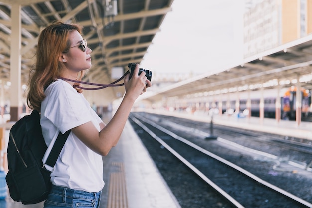 Giovane viaggiatore con fotocamera sulla stazione