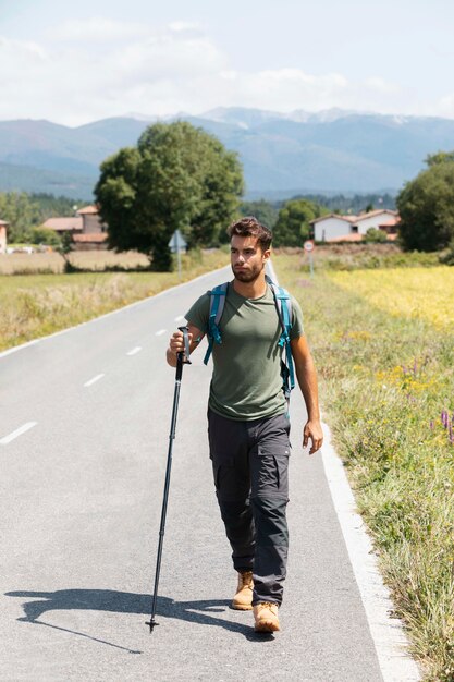 Giovane viaggiatore maschio in alava che tiene un bastone da trekking