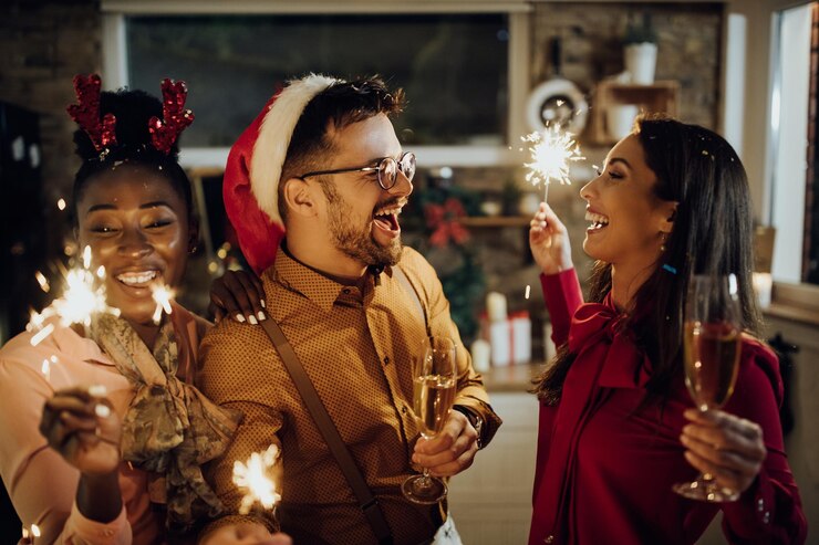 Foto gratuito giovani adulti allegri che bevono champagne e usano le stelle filanti alla festa di capodanno a casa