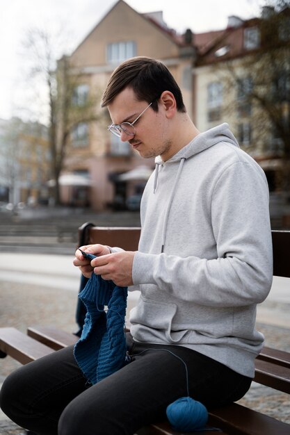 Giovani adulti che lavorano a maglia all'esterno