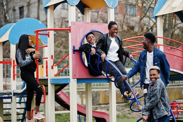 Giovani amici africani millennial sul parco giochi scivolano e oscillano Felici i neri che si divertono insieme Concetto di amicizia della Generazione Z