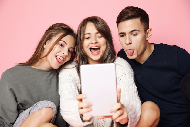 Giovani amici che fanno selfie sul tablet sul rosa