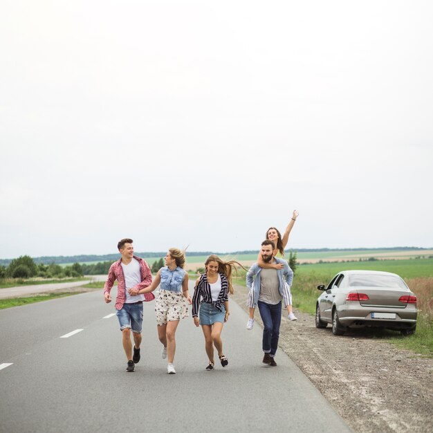 Giovani amici che godono insieme sulla strada di campagna