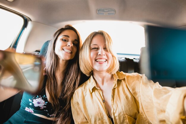 Giovani amici che prendono selfie in auto