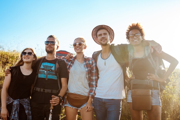 Giovani amici che sorridono, rallegrandosi, esaminando la distanza, stando nel campo