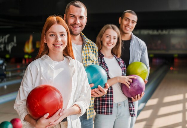 Giovani amici felici che tengono il colpo medio delle palle da bowling