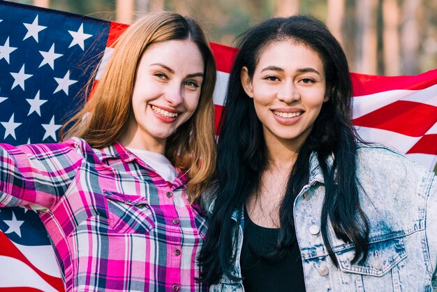 Giovani amici femminili che fluttua nella bandiera americana il giorno dell&#39;indipendenza