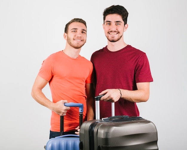 Giovani amici in magliette luminose in piedi con le valigie