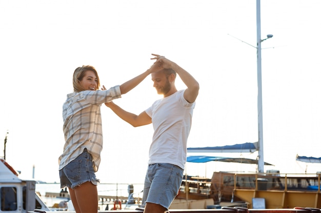 Giovani belle coppie che camminano in riva al mare, sorridenti, skateboard.