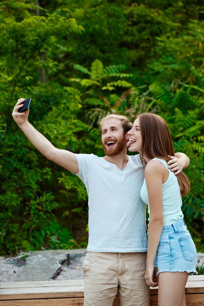 Giovani belle coppie che fanno selfie, sorridendo, camminando nel parco