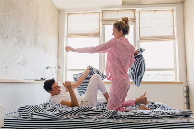 Giovani belle coppie che si divertono sul letto la mattina stanno insieme a casa da soli