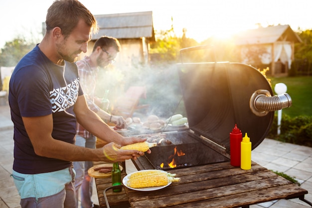 Giovani che arrostiscono barbecue sulla griglia nella campagna del cottage.