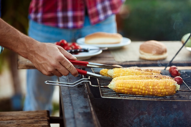 Giovani che arrostiscono barbecue sulla griglia nella campagna del cottage.