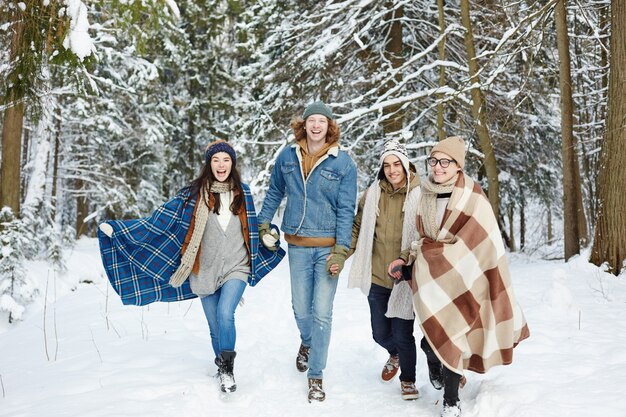 Giovani che corrono nella foresta di inverno