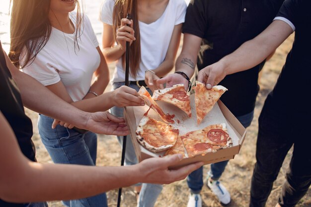 Giovani che mangiano pizza e che fumano shisha sulla spiaggia