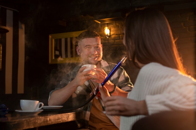 Giovani che svapano da un narghilè in un bar