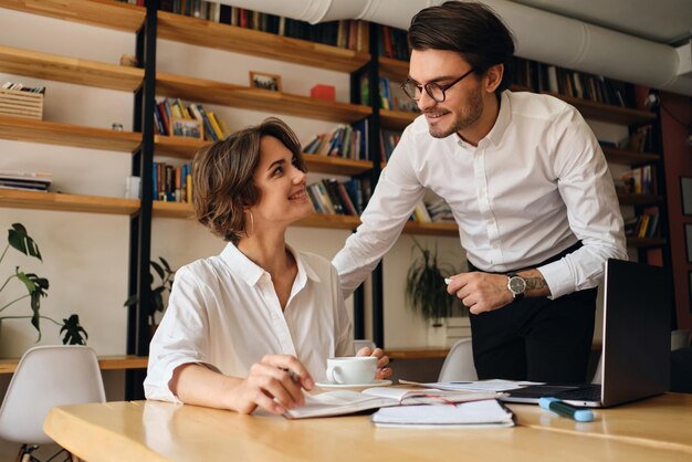 Giovani colleghi di lavoro attraenti che si guardano con gioia mentre lavorano insieme su un nuovo progetto in un ufficio moderno