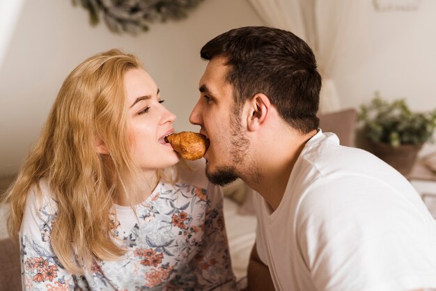 Giovani coppie adorabili che dividono un croissant