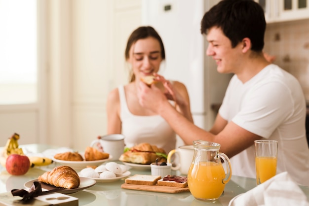 Giovani coppie adorabili che servono insieme prima colazione