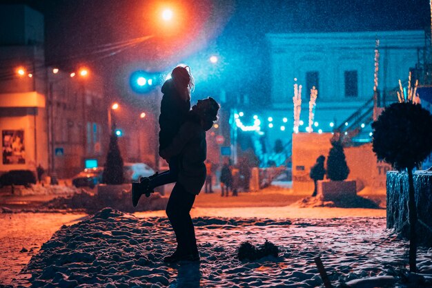 Giovani coppie adulte l'una nelle braccia dell'altra sulla strada innevata