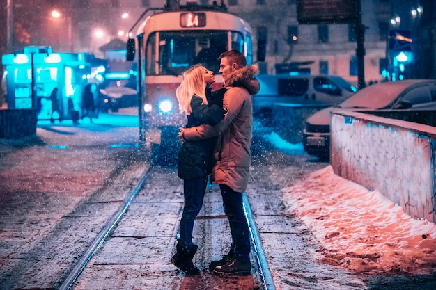 Giovani coppie adulte sulla linea del tram innevata