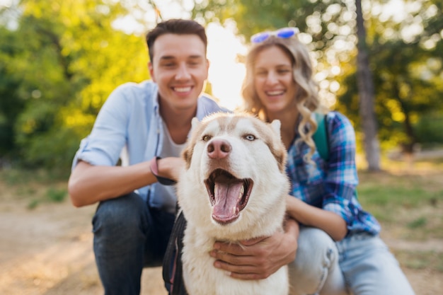 Giovani coppie alla moda che camminano con il cane in strada. uomo e donna felici insieme alla razza husky,