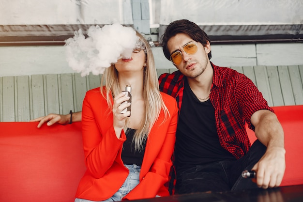 Giovani coppie alla moda con vape in una città