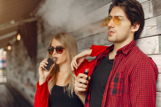 Giovani coppie alla moda con vape in una città