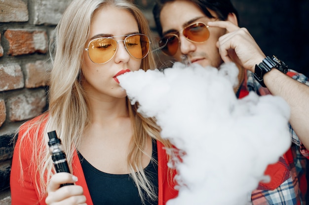 Giovani coppie alla moda con vape in una città