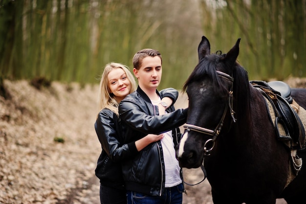 Giovani coppie alla moda nell'amore vicino al cavallo alla foresta di autunno