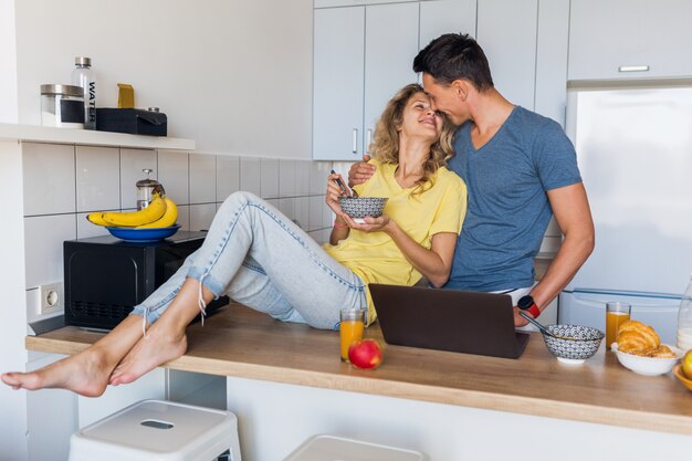 Giovani coppie attraenti dell'uomo e della donna che mangiano colazione insieme mattina alla cucina