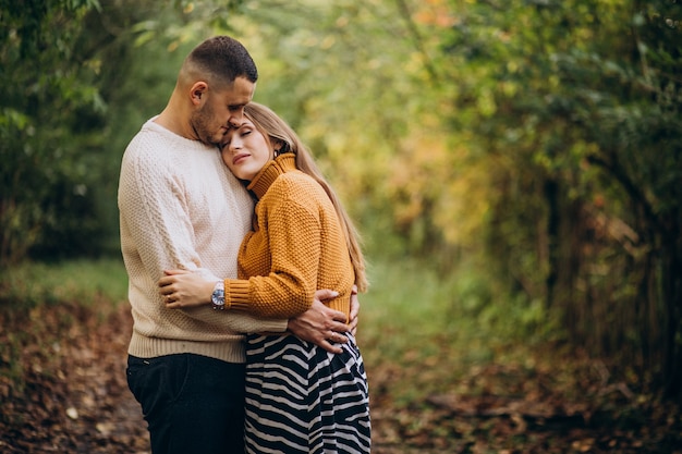 Giovani coppie che abbracciano nella foresta di autunno