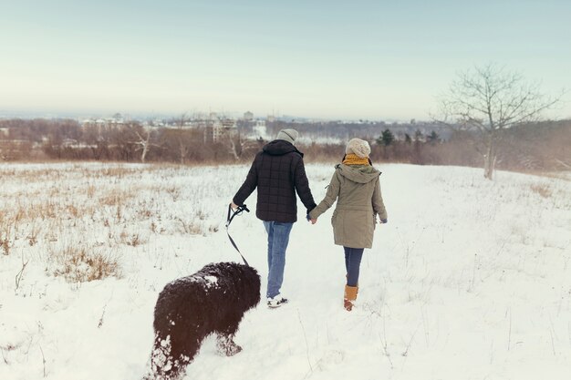 Giovani coppie che camminano con un cane in un giorno di inverno