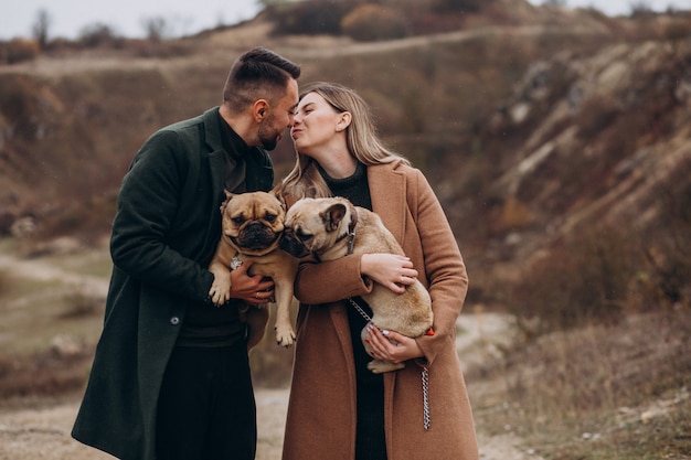 Giovani coppie che camminano i loro bulldog francesi in parco