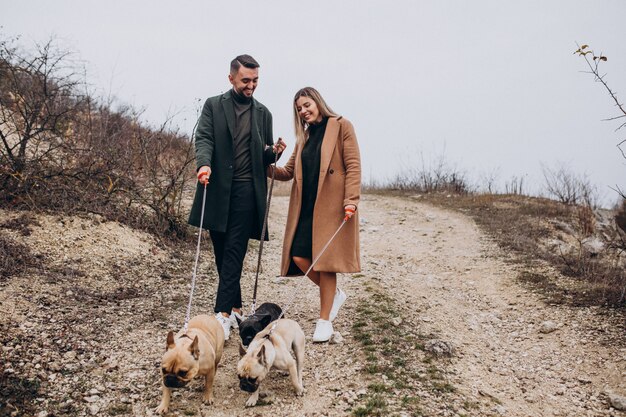 Giovani coppie che camminano i loro bulldog francesi in parco