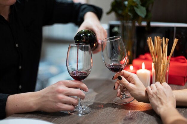 Giovani coppie che celebrano il giorno di san valentino mentre pranzano e bevono vino insieme