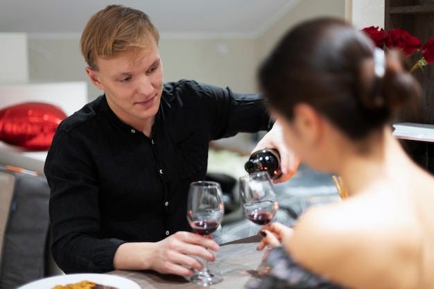 Giovani coppie che celebrano il giorno di san valentino mentre pranzano e bevono vino insieme