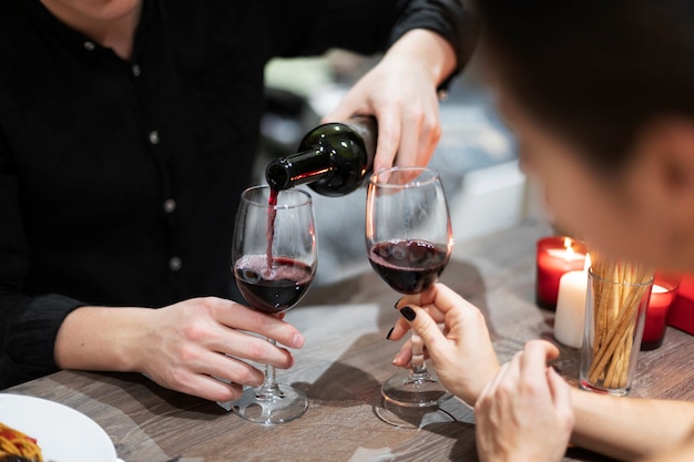 Giovani coppie che celebrano il giorno di san valentino mentre pranzano e bevono vino insieme