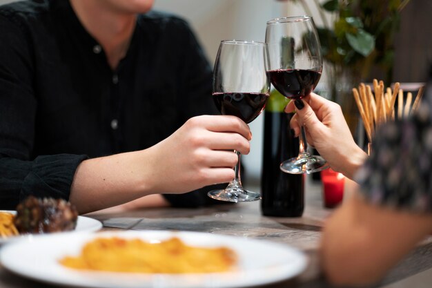 Giovani coppie che celebrano il giorno di san valentino mentre pranzano e bevono vino insieme