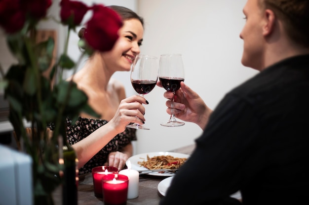 Giovani coppie che celebrano il giorno di san valentino mentre pranzano e bevono vino insieme