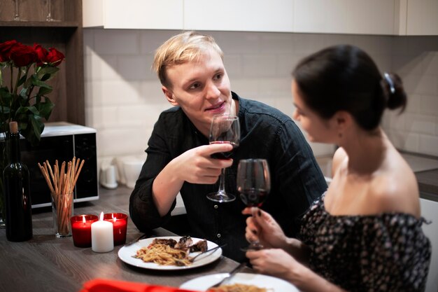 Giovani coppie che celebrano il giorno di san valentino mentre pranzano e bevono vino insieme