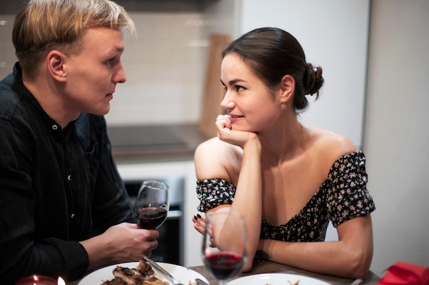 Giovani coppie che celebrano il giorno di san valentino mentre pranzano e bevono vino insieme