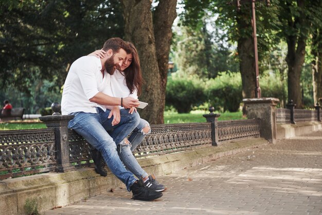 Giovani coppie che esaminano uno smartphone un giorno soleggiato nella città