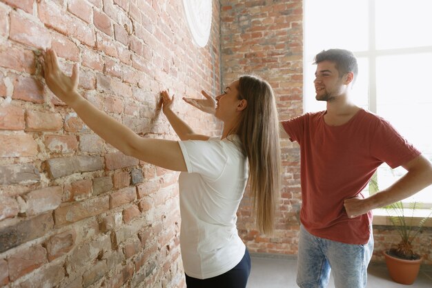 Giovani coppie che fanno insieme riparazione dell'appartamento. Uomo e donna sposati che fanno rifacimento o ristrutturazione della casa