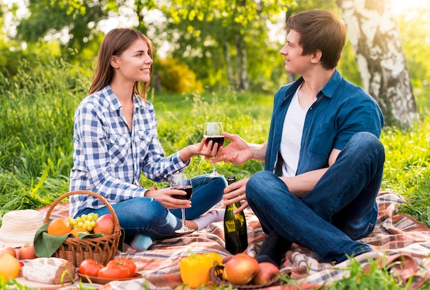 Giovani coppie che hanno picnic con cibo e vino