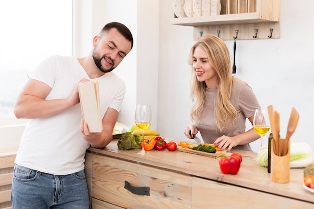 Giovani coppie che leggono un libro in cucina